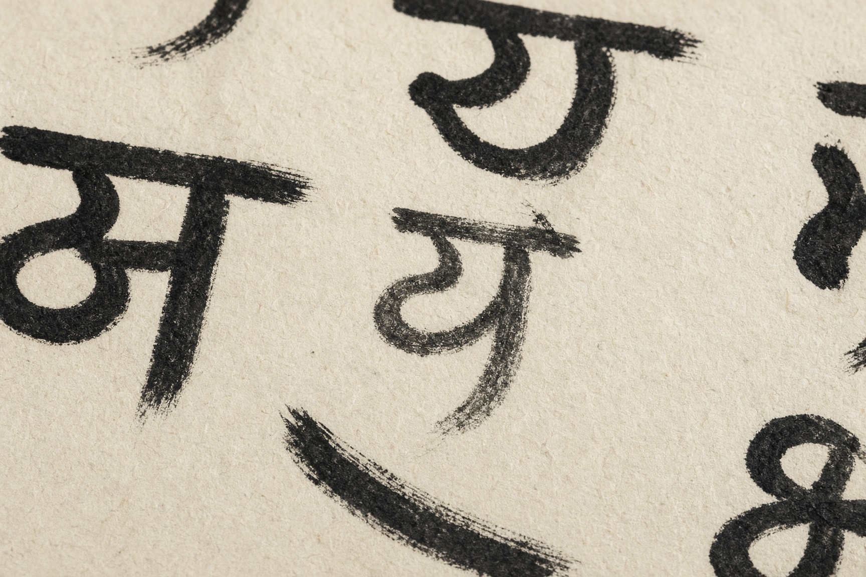 Devanagari letterforms in black ink on handmade paper.